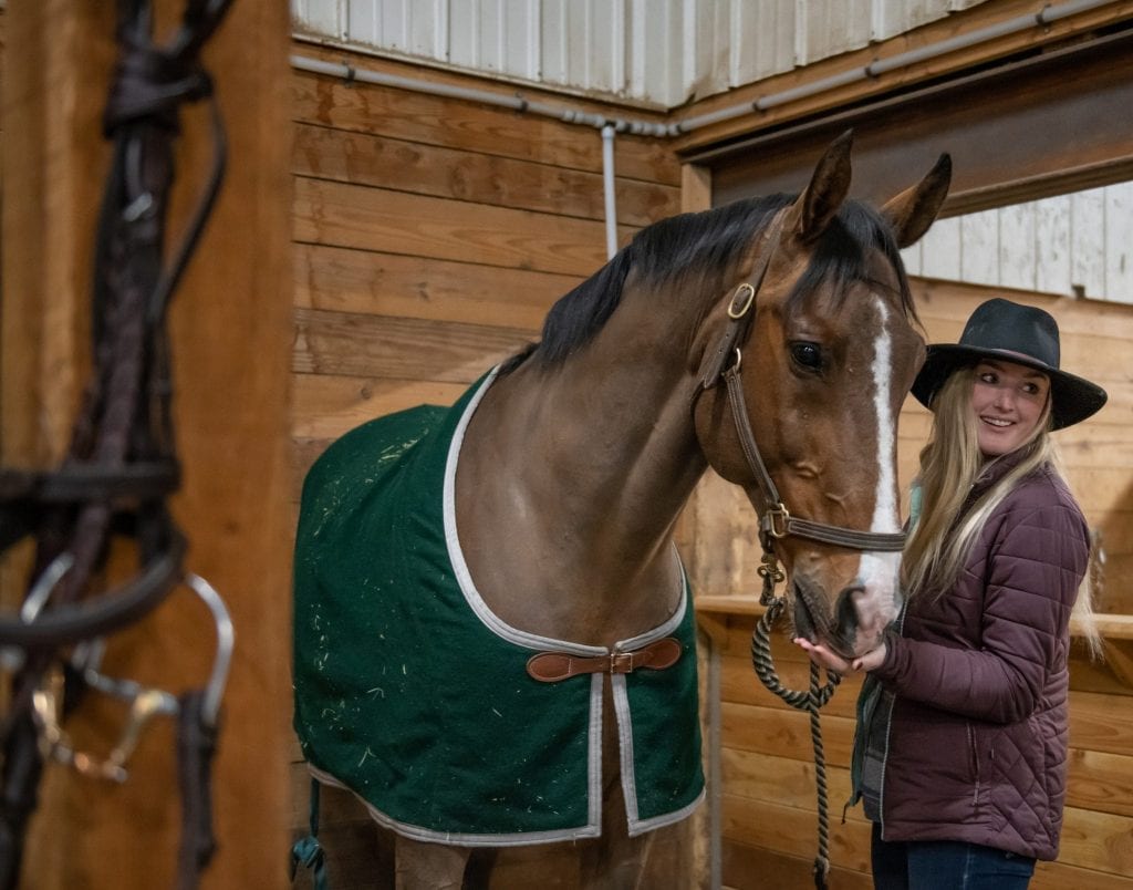 woman with horse in winter stable