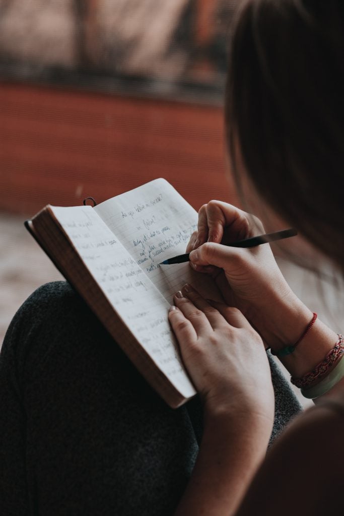 A woman journals in a lined notebook.