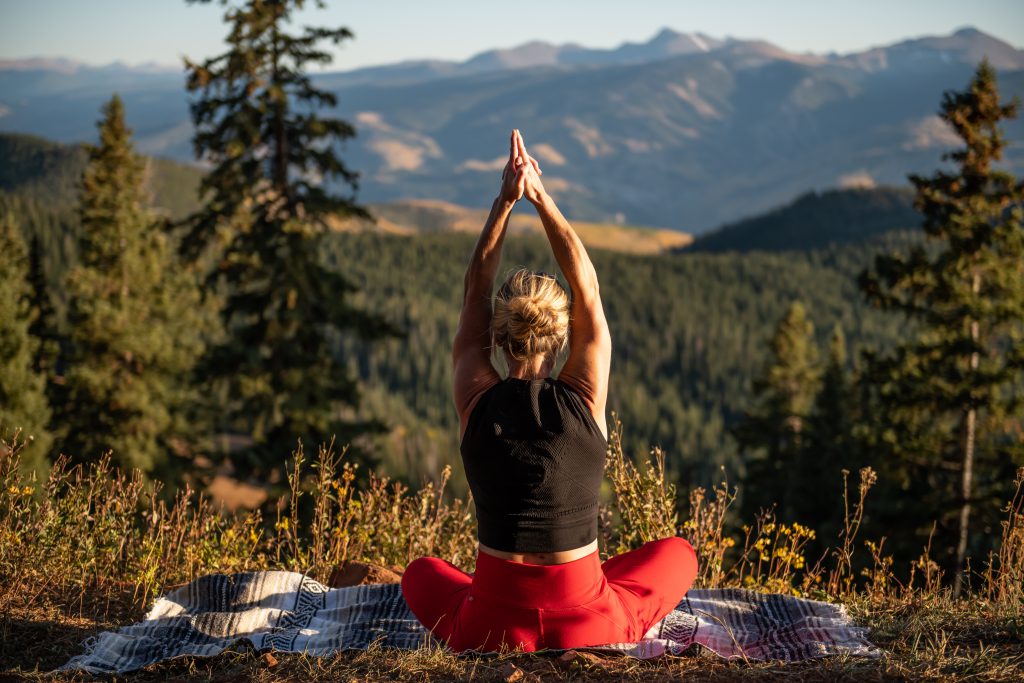 A client practices meditation outside of All Points North Lodge overlooking the Colorado mountains.