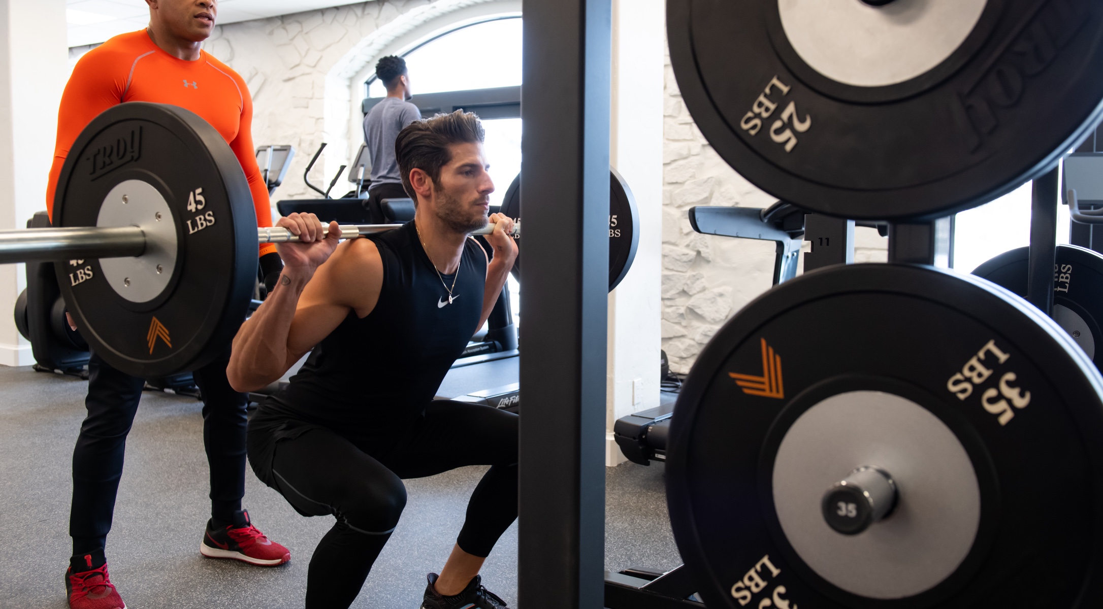 A client squats a barbell in the gym at All Points North Lodge.