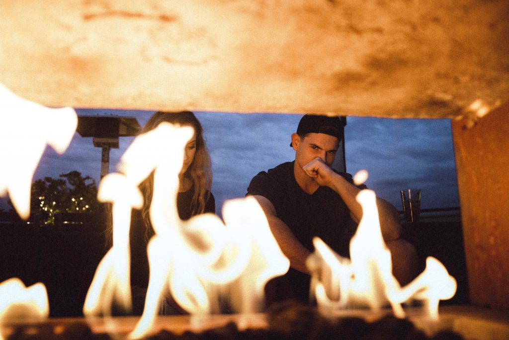 A couple having a disagreement by a fire.