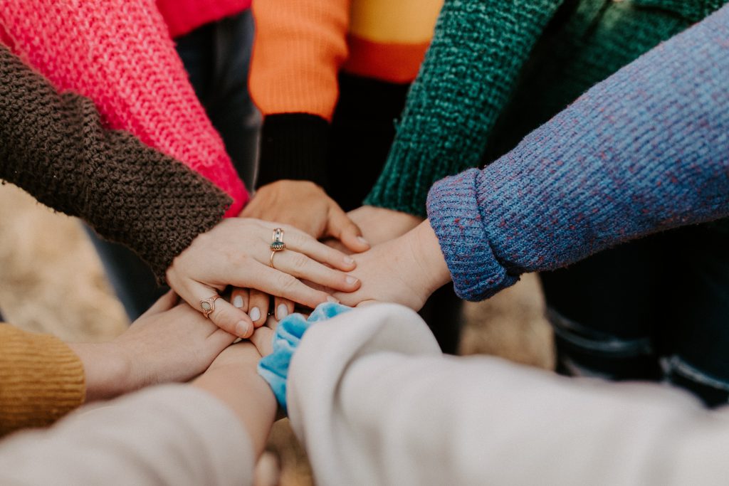 A group of women pile their hands together.