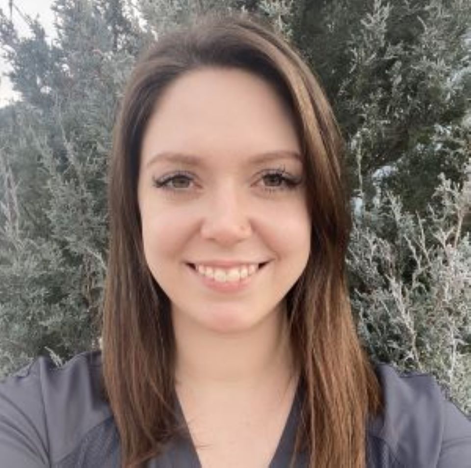 Jessica smiling in front of an evergreen tree