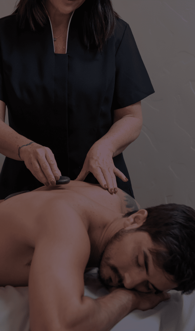 A man lays on a massage table while a masseuse works on his shoulder at the spa at APN.