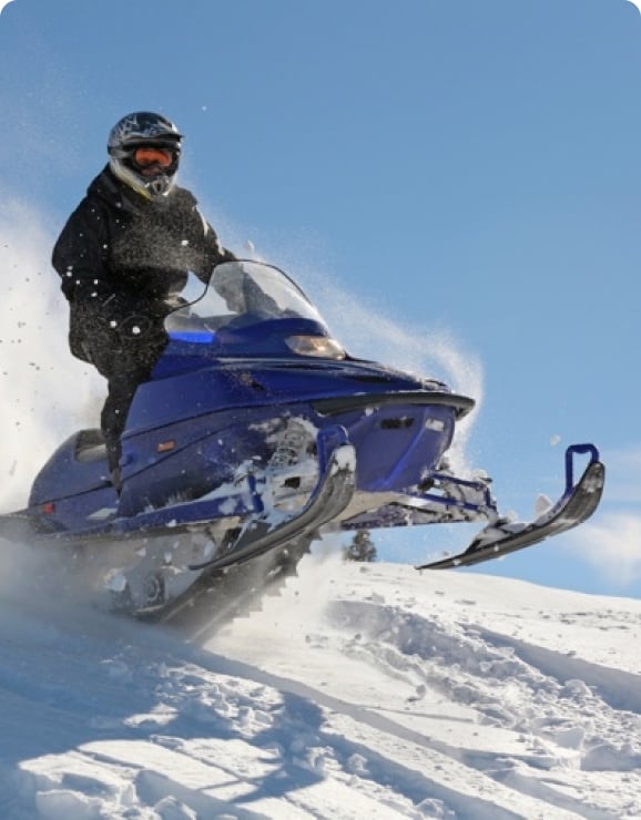 A client snowmobiles over a hill.