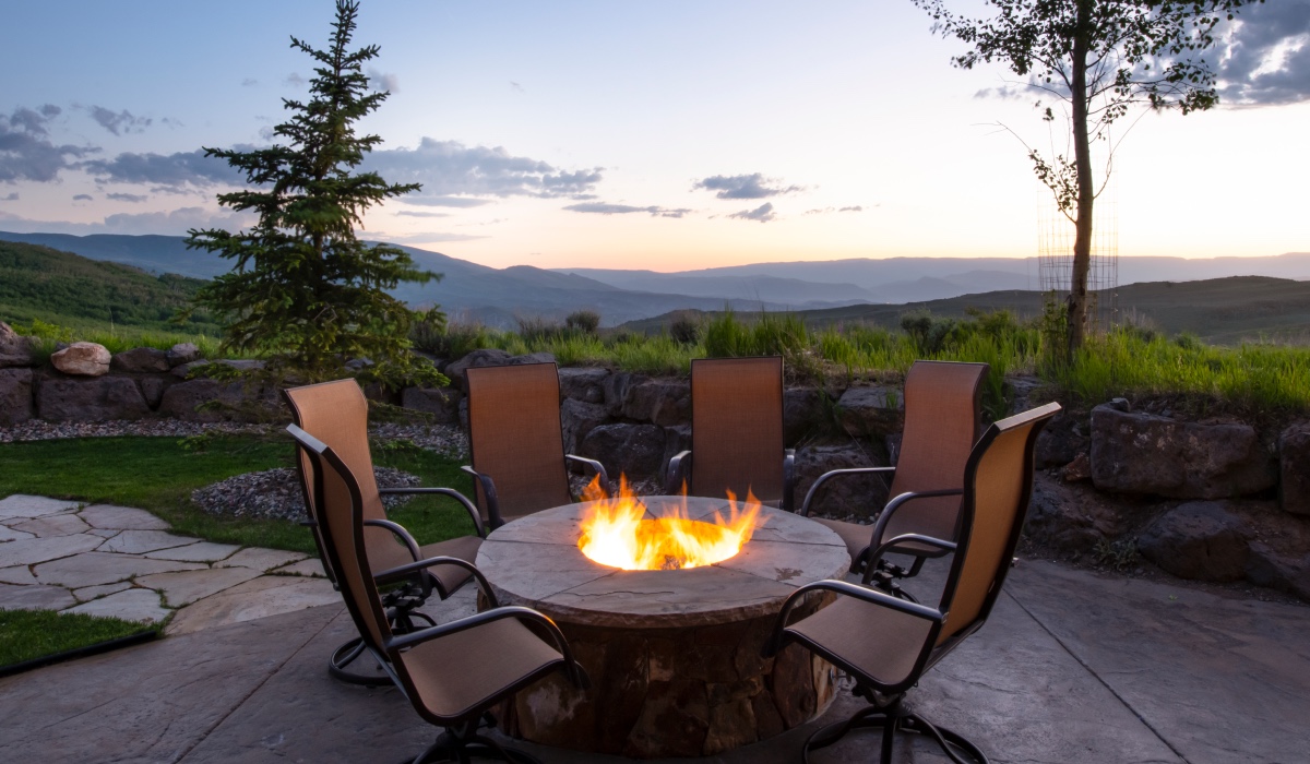 Chairs around an outdoor fire pit with views of the Colorado mountains