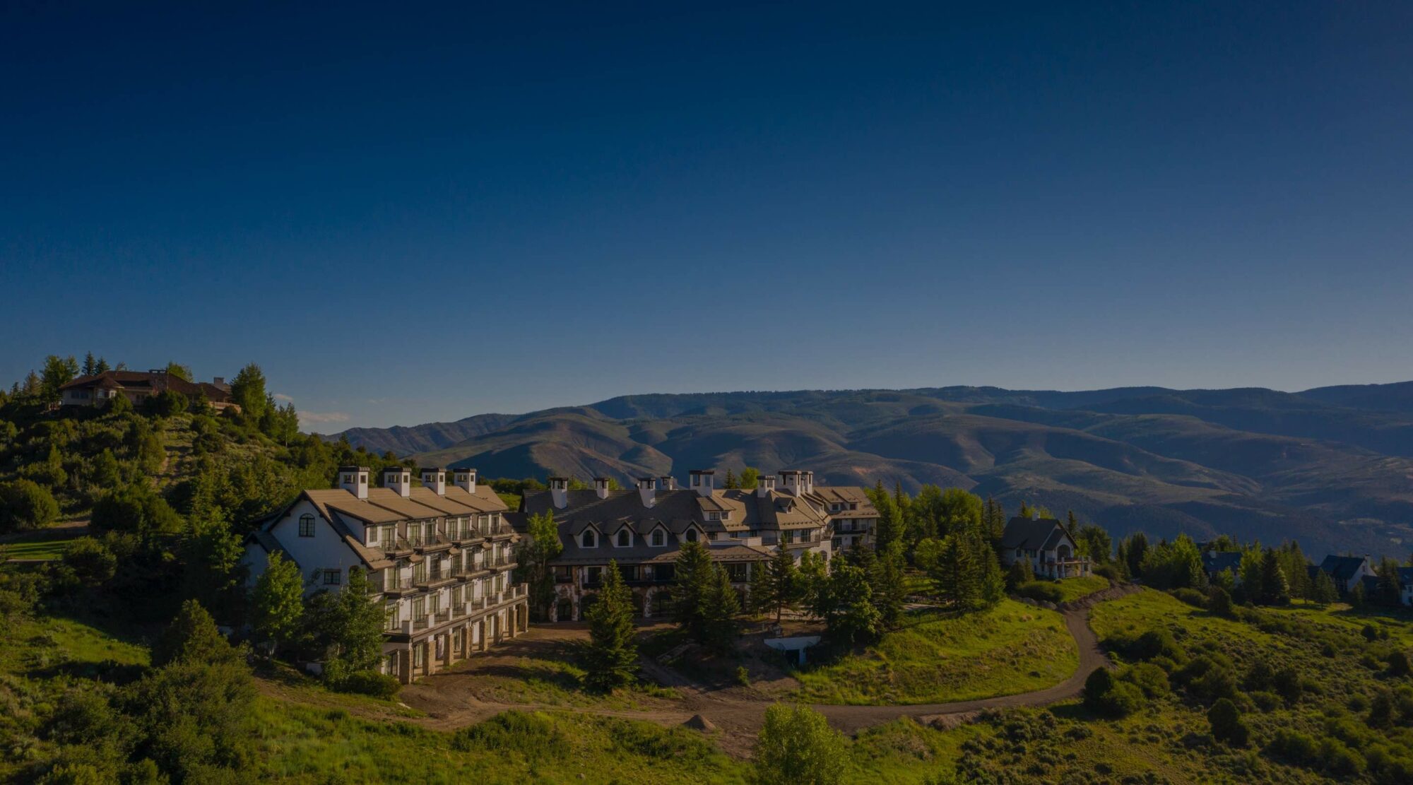 Aerial view of the All Points North Lodge, surrounded by forest-covered mountains