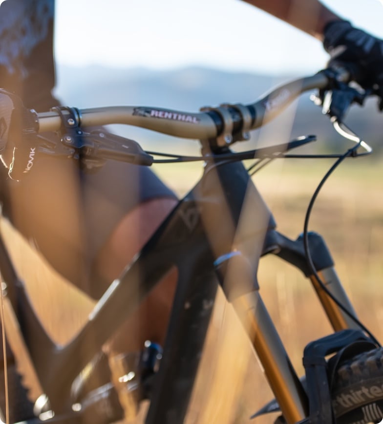 A man on a mountain bike with a focus on the handlebars.