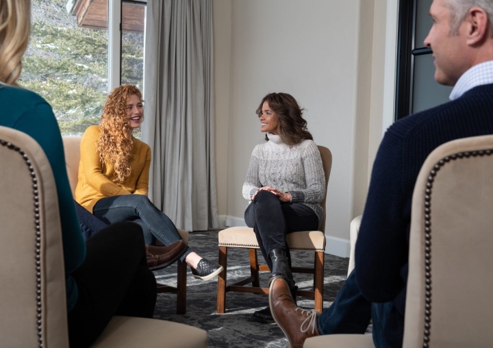 A client sits in a group setting with therapists at All Points North Lodge.