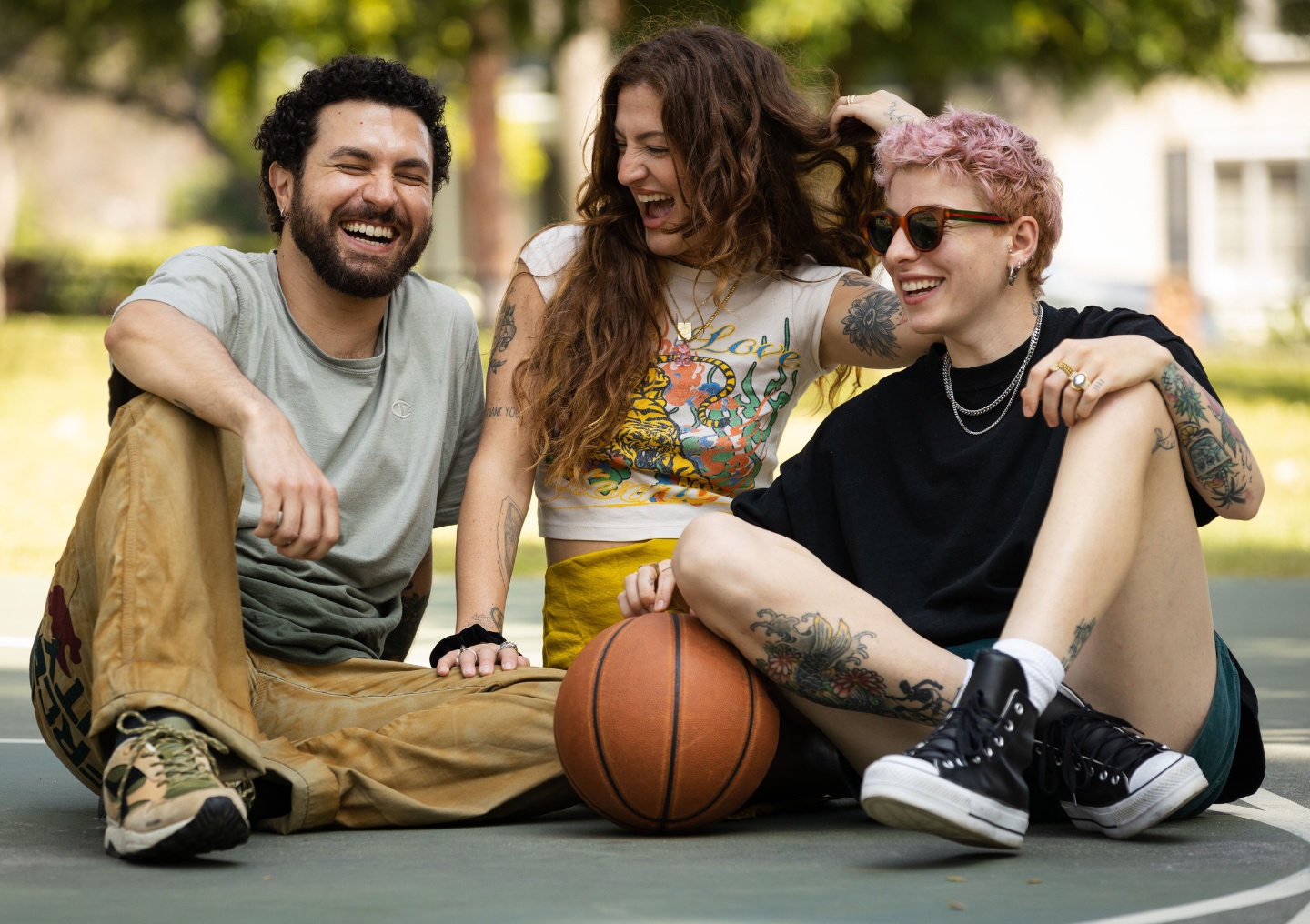 A group of friends laugh together at the basketball court.