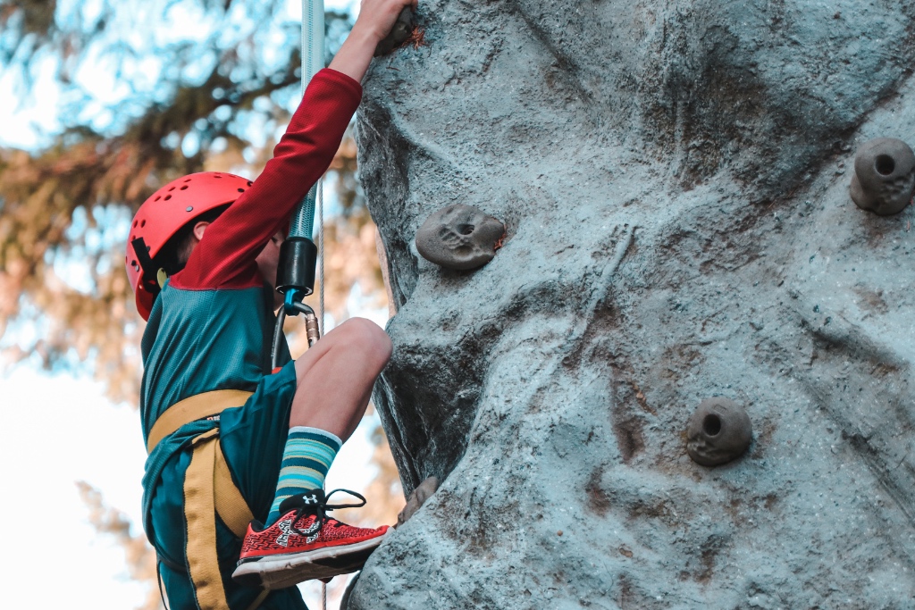 A man reaches up while rock climbing outdoors.