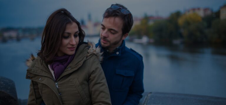 An unsure couple stands together for a photo.