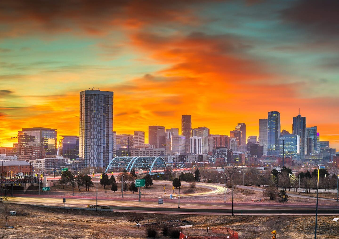 Denver skyline at sunset, showcasing modern buildings and a bridge, reflecting the vibrant atmosphere of the city, relevant to mental health recovery programs offered at All Points North Lodge in Boulder, Colorado.