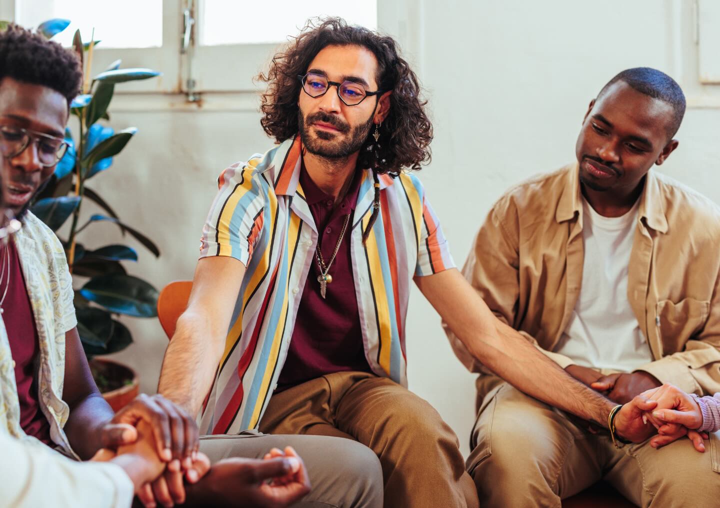 Three people listen during a group therapy session at All Points North while holding hands.