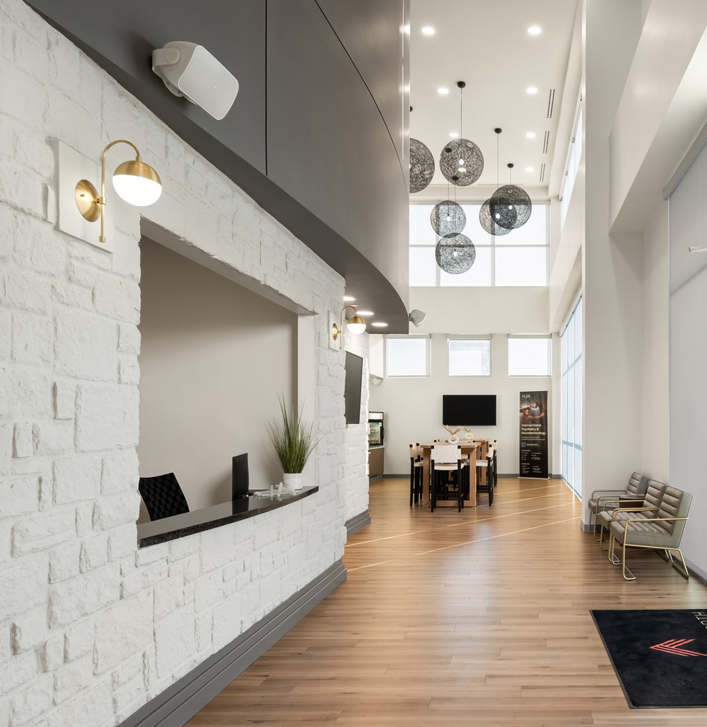 The entrance of APN Dallas-Fort Worth: natural light streams into an open foyer area with an enclosed reception desk to the left and wicker light fixtures hanging from the ceiling on the right.