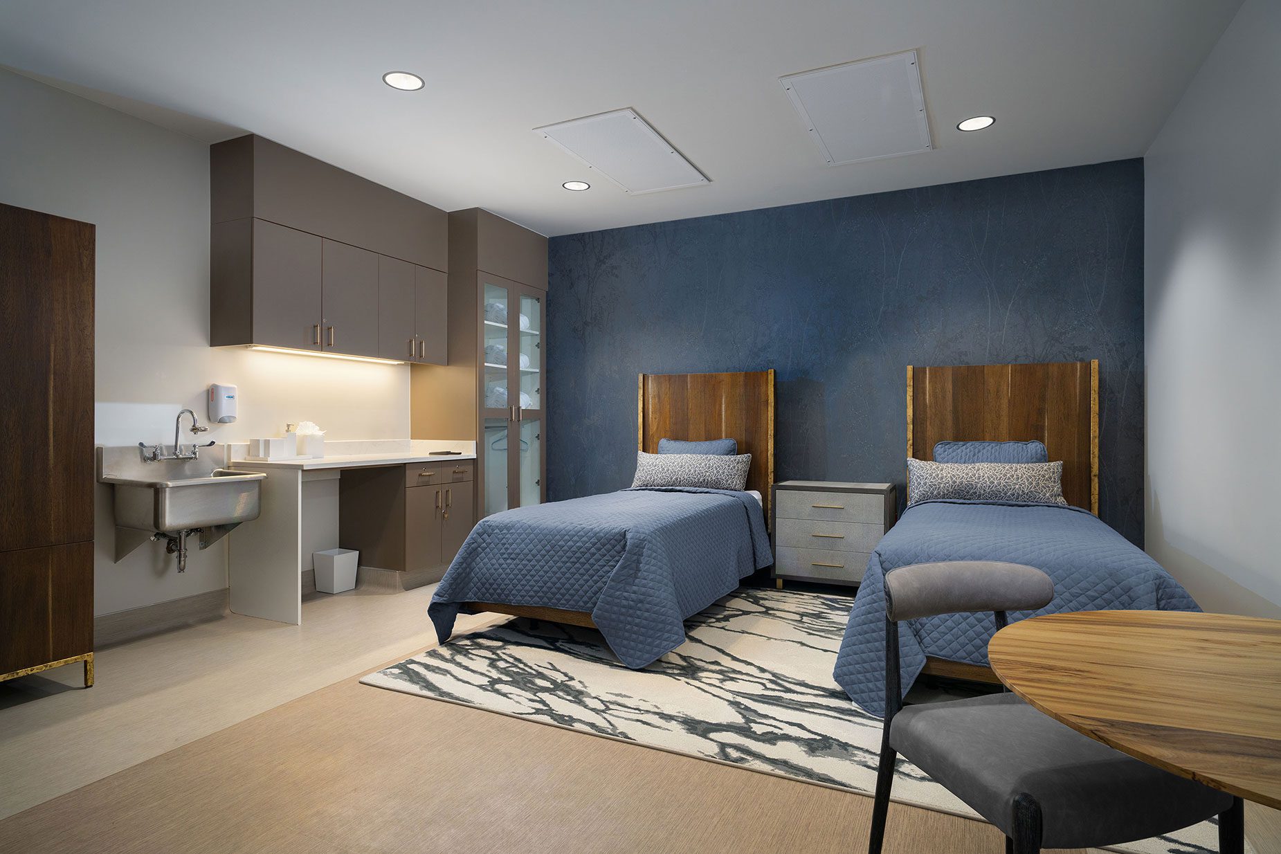 Luxury treatment room at All Points North Denver featuring two twin beds with blue bedding, modern furnishings, and a calming color scheme, designed for personalized detox and intensive outpatient care.