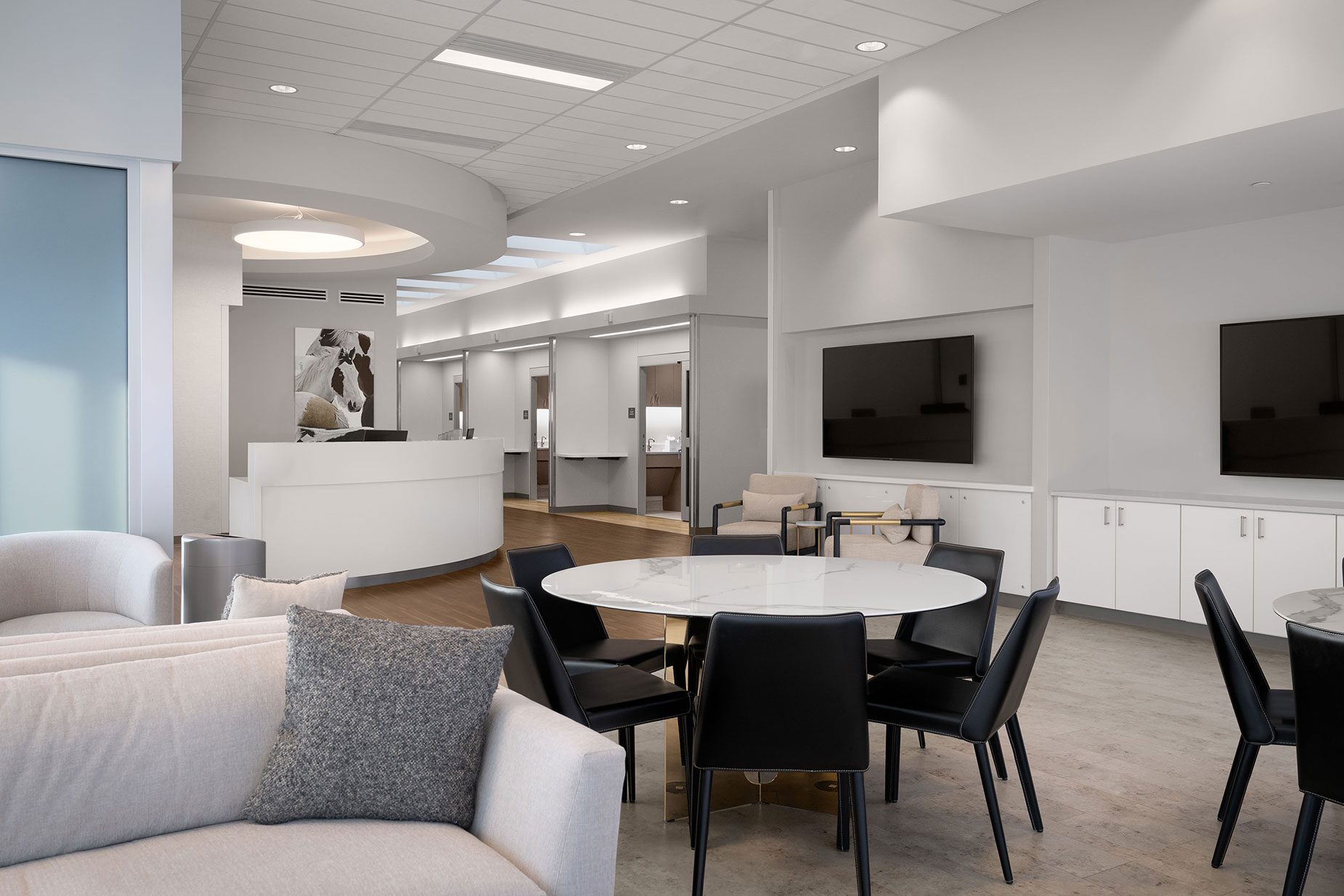 Modern treatment center interior featuring a welcoming reception area, circular table with black chairs, soft seating, and multiple therapy rooms, emphasizing luxury and personalized care for addiction and mental health recovery.