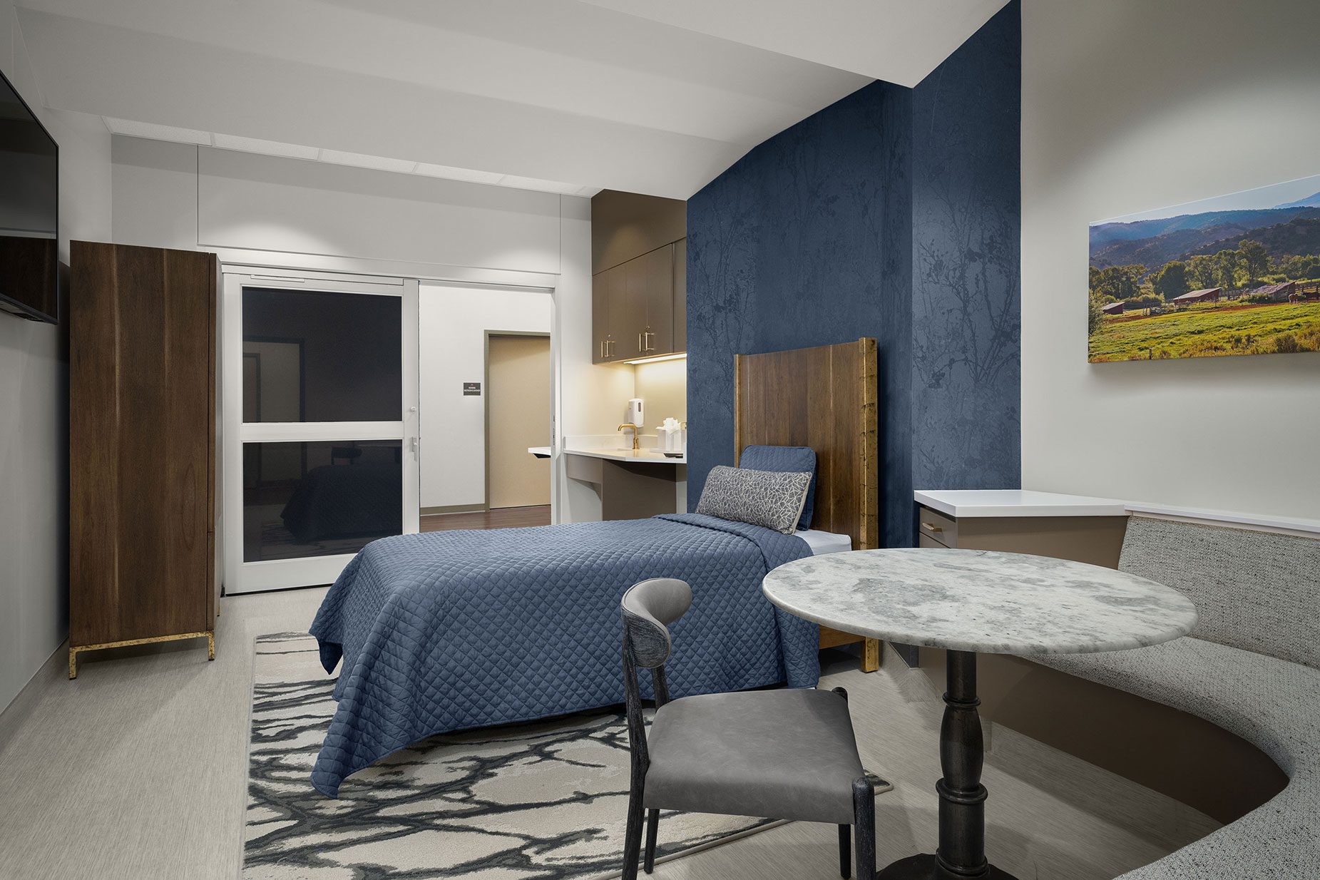 Luxury treatment room at All Points North Denver featuring a hospital bed with blue bedding, modern furnishings, and a calming atmosphere, reflecting personalized care for addiction recovery.