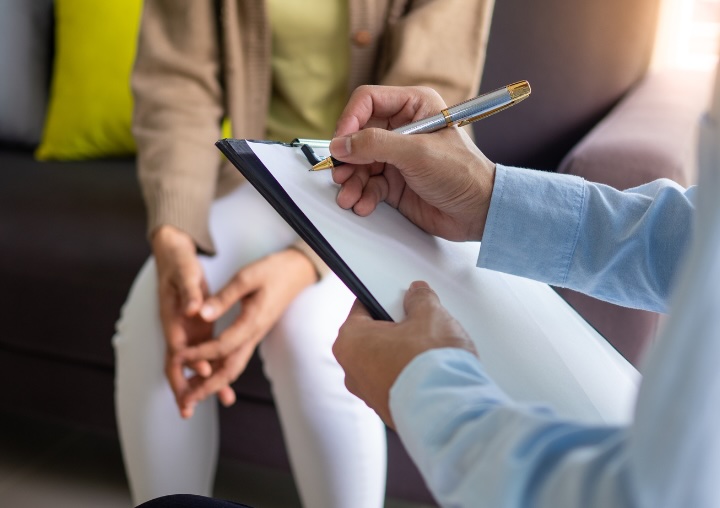 A therapist takes notes for a client during an intake appointment.